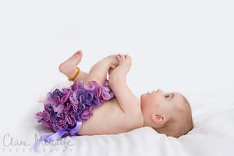Baby grabbing feet with frilly knickers