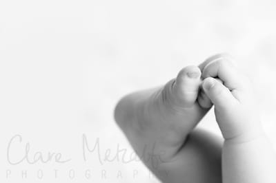 Black and white close up image of baby grabbing foot