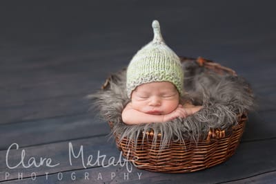 Newborn asleep in basket wearing pixie hat