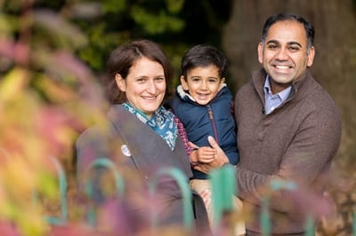 Autumnal photograph of family smiling in a park in Ealing. 