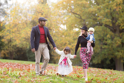 Photograph of a family walking through autumn leaves in park Eastcote
