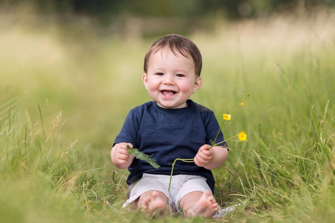 Photograph of smiling baby outdoors in a field in Harrow, London by Clare Metcalfe family photography
