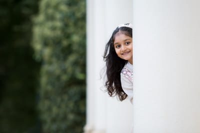 Photograph of girl looking out from behind pillar at Kenwood House. 