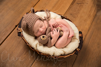 Newborn baby dressed as teddy bear asleep in a basket