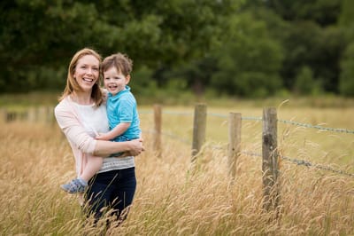 Photograph of mother holding son in field of long grass in Harrow on the Hill. 