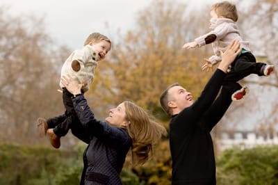 Photograph of parents throwing twins in the air. 
